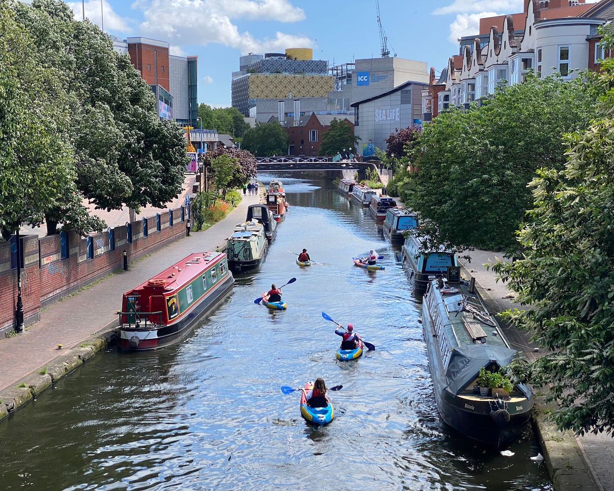 A photograph of Birmingham canals with people kayaking during Summer