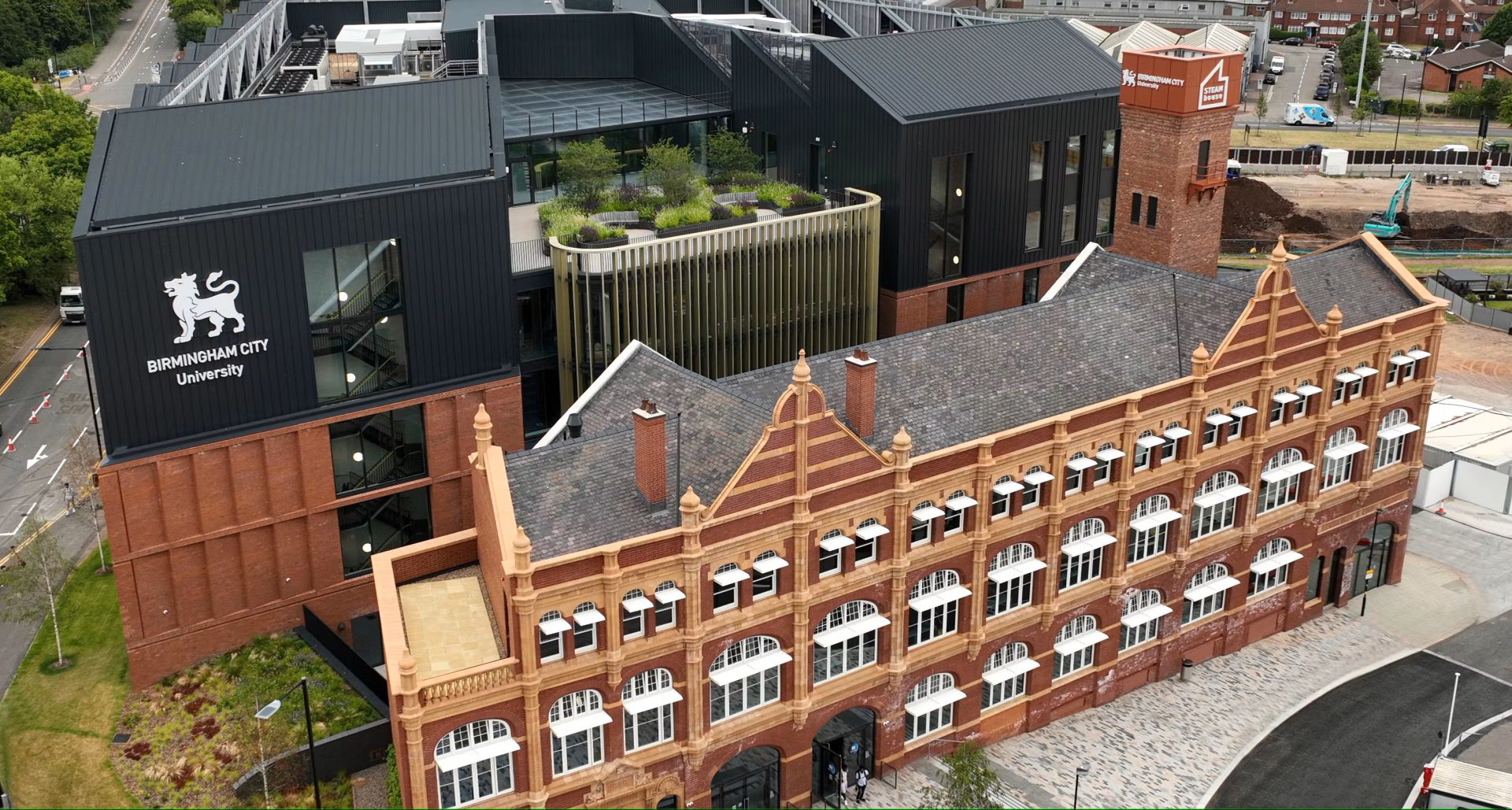 A top down photograph of the STEAMhouse building. The building is made up mostly of red bricks, with many windows, and a garden on the roof.